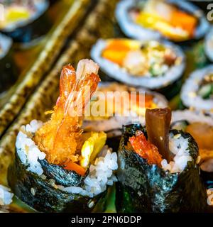 Gimbap è un piatto coreano a base di riso cotto e ingredienti come verdure, pesce e carni che vengono arrotolati in gim (fogli essiccati di alghe) e. Foto Stock