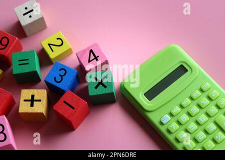 Calcolatrice e cubetti di legno con simbolo matematico. Educazione e concetto matematico Foto Stock