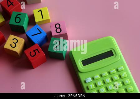Calcolatrice e cubetti di legno con simbolo matematico. Educazione e concetto matematico Foto Stock