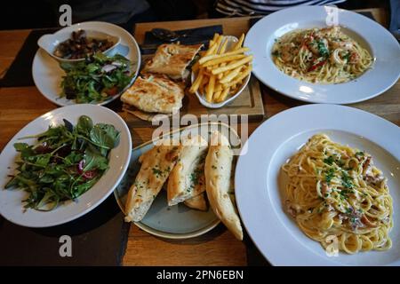 Insalata balsamica di razzo selvatico e pane all'aglio al burro servito con pasta Carbonara di pesce e patate fritte zeppa francese Foto Stock
