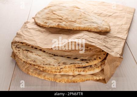 Diversi pita appena sfornati in una borsa di carta, primo piano, su un tavolo di legno. Foto Stock