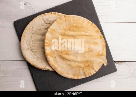 Due pita al forno, primo piano, su un tavolo di legno, vista dall'alto. Foto Stock