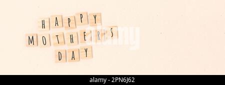 Felice giorno delle madri. Banner con citazione in blocchi di legno con lettere su sfondo beige. Foto Stock
