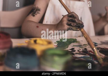 Scena giocosa delle mani di un bambino con un pennello, che si impegnano in un'esplorazione dell'arte sostenibile e rispettosa dell'ambiente. Foto Stock