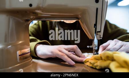 Primo piano delle mani della donna mentre si utilizza una macchina da cucire Foto Stock