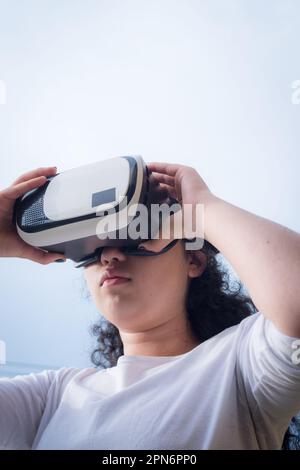 Giovane donna che indossa una maschera per la realtà virtuale in una giornata nuvolosa Foto Stock