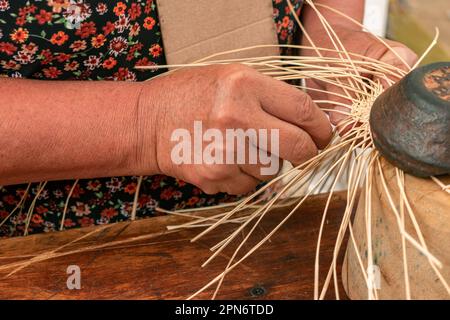 Particolare delle mani di un artigiano colombiano che tessono un cappello Foto Stock