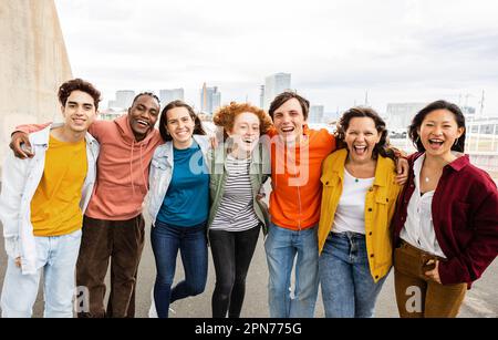 Felice gruppo di amici teenager che si abbraccia sorridendo alla fotocamera fuori Foto Stock