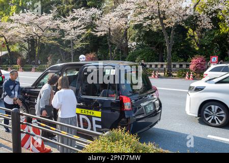 Aprile 2023, Toyota JPN ibrido nero taxi ferma a Tokyo per prendere una signora tariffa e porte aperte, Giappone, Asia Foto Stock