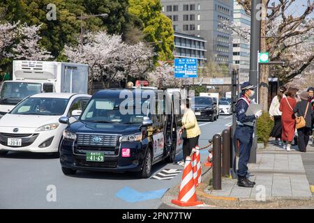 Aprile 2023, Toyota JPN ibrido nero taxi ferma a Tokyo per prendere una signora tariffa e porte aperte, Giappone, Asia Foto Stock