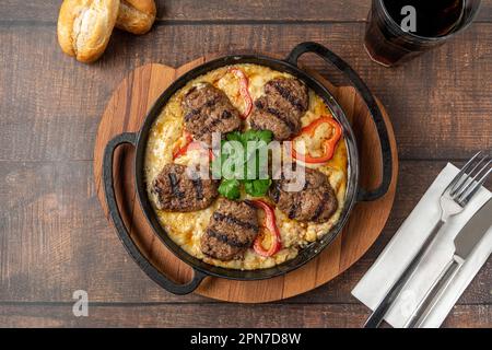 Polpette con salsa all'alinazik. Polpette turche tradizionali su purea di melanzane in padella di ghisa Foto Stock