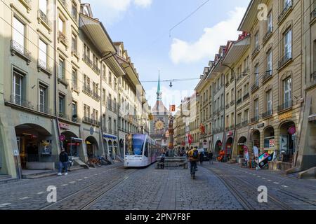 Berna, Svizzera - 23 febbraio 2023: Vista sulla via marktgasse, con il tram, la fontana Schuzenbrunnen, la torre dell'orologio Zytglogge, locali, e visitare Foto Stock