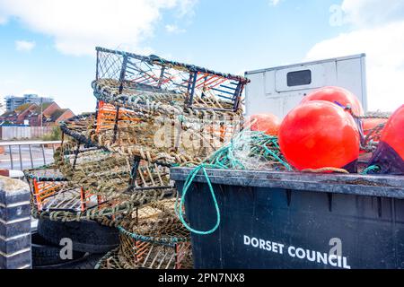 Granchio ed altre pentole di attrezzatura di pesce accatastate e immagazzinate sul molo a Poole Harbour in Dorset, Regno Unito Foto Stock