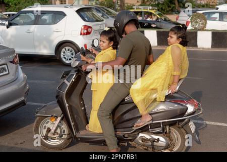 Un padre a Mumbai, in India, prende le sue due figlie vestite in modo identico per un giro sul suo scooter a motore Foto Stock
