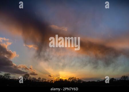 Raggi di sole che si infrangono tra le nuvole al tramonto Foto Stock