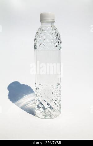 Piccola bella bottiglia di plastica piena di acqua isolata su bianco. Liquido trasparente in una bottiglia decorativa con tappo Foto Stock