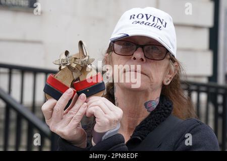 Catherine Doyle Ellis tiene in mano le scarpe della nipote Jacqueline che morì nel bombardamento di Dublino/Monaghan del 1974 come membri del Pat Finucane Centre e Justice for the Forgotten campagne hanno messo le scarpe dei loro familiari uccisi durante i problemi dell'Irlanda del Nord al di fuori degli edifici di corte a Belfast in protesta Contro le difficoltà dell'Irlanda del Nord (eredità e riconciliazione) Billl. Data immagine: Lunedì 17 aprile 2023. Foto Stock