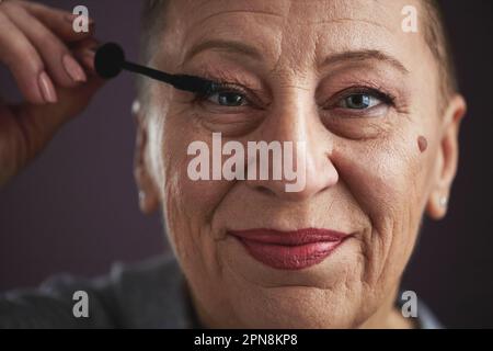 Primo piano ritratto di donna baldosa maturo fare trucco e sorridere alla macchina fotografica Foto Stock