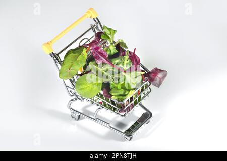 Un carrello pieno di insalata mista sullo sfondo bianco, un primo piano. Un supermercato, prodotti alimentari Foto Stock