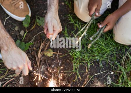 Vista dall'alto primo piano di padre e figlio che iniziano il fuoco insieme mentre si camminano nella foresta Foto Stock