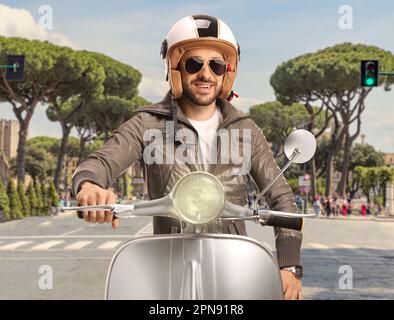 Ragazzo in giacca di pelle seduto su uno scooter per le strade di Roma, Italia Foto Stock