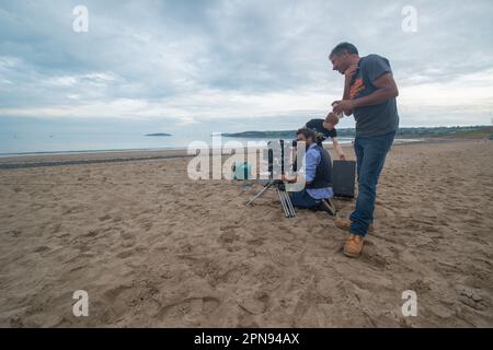 Cineequipaggio in località costiera utilizzando una fotocamera ROSSA Foto Stock