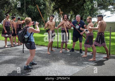 Turisti in posa per una fotografia con artisti Maori presso Waitangi Treaty Grounds, North Island, Nuova Zelanda Foto Stock