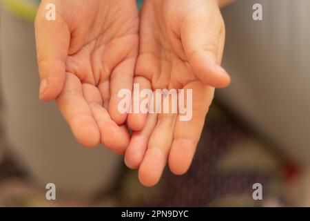 mani tese dei bambini su un primo piano sfocato che chiede Foto Stock