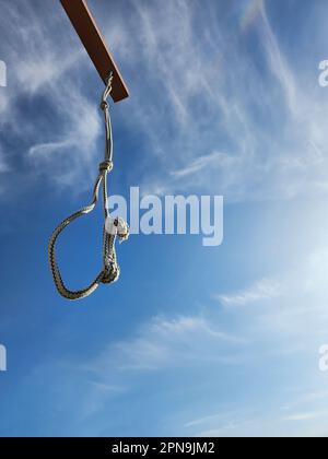 Il cappio della corda è sospeso su un mazzetto contro il cielo blu con le nuvole. Foto di alta qualità Foto Stock