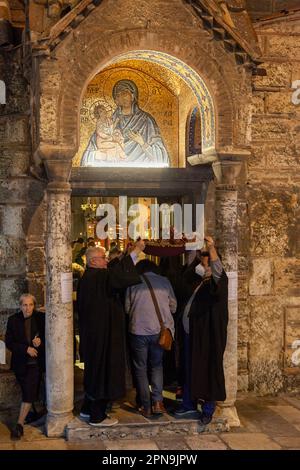 I credenti vengono alla chiesa bizantina di Panagia Kapnikarea durante l'Epitaph (Venerdì Santo), passando sotto un tappeto che rappresenta l'Epitaph. Foto Stock
