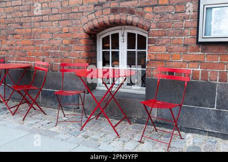 Arredamento moderno in metallo per esterni, sedie rosse e tavolo all'esterno del caffè in Europa. Metafora e symoblism per l'attesa, nessun cliente, distruzione vuota, covid, Foto Stock