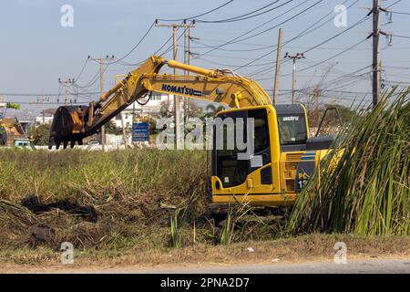 BANGKOK, THAILANDIA, 21 2023 GENNAIO, un escavatore sta lavorando in un prato accanto alla strada Foto Stock