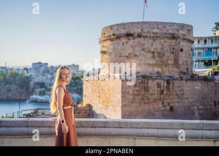 Donna turistica sullo sfondo della Torre Hidirlik di Antalya sullo sfondo della baia mediterranea dell'antico quartiere di Kaleici, Turchia Foto Stock