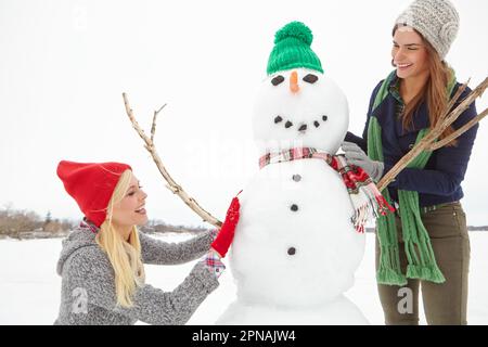 Vuoi costruire un pupazzo di neve? due amici che costruiscono un pupazzo di neve insieme. Foto Stock