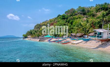 Un piccolo villaggio costiero con colorate barche banca in legno sulla spiaggia, situato a San Antonio Barangay sull'Isola Verde, Provincia di Batangas, Filippine Foto Stock