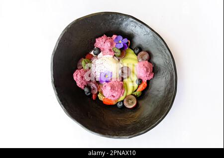 Dessert con gelato e avocado, decorato con fiori su sfondo bianco Foto Stock