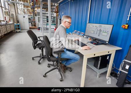 PRODUZIONE - 05 aprile 2023, Amburgo: Thomas Willner, ingegnere di processo e capo progetto di READi-PTL (distillazione reattiva), è presente presso un monitor dell'impianto con un reattore per la conversione dei materiali di scarto (grassi usati) nell'impianto pilota del dipartimento di ingegneria di processo presso il Life Sciences Campus di HAW. L'impianto pilota è progettato per convertire i materiali di scarto, come i grassi usati e i rifiuti di plastica, in un sostituto del petrolio pesante privo di olio e privo di carbonio. Il sostituto del petrolio (olio vegetale cracked CVO) può essere usato per produrre combustibili liquidi come benzina e diesel, così come plastica e molto m Foto Stock