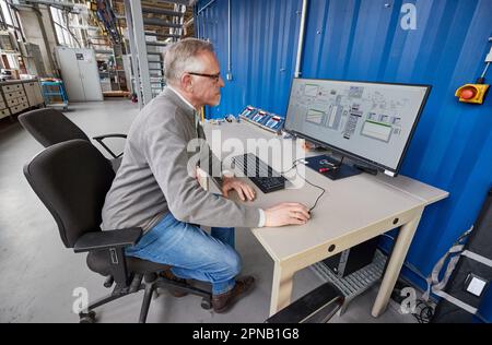 PRODUZIONE - 05 aprile 2023, Amburgo: Thomas Willner, ingegnere di processo e capo progetto di READi-PTL (distillazione reattiva), è presente presso un monitor dell'impianto con un reattore per la conversione dei materiali di scarto (grassi usati) nell'impianto pilota del dipartimento di ingegneria di processo presso il Life Sciences Campus di HAW. L'impianto pilota è progettato per convertire i materiali di scarto, come i grassi usati e i rifiuti di plastica, in un sostituto del petrolio pesante privo di olio e privo di carbonio. Il sostituto del petrolio (olio vegetale cracked CVO) può essere usato per produrre combustibili liquidi come benzina e diesel, così come plastica e molto m Foto Stock