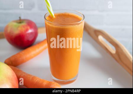 Succo di mela di carota appena spremuto in un bicchiere con una cannuccia da bere Foto Stock