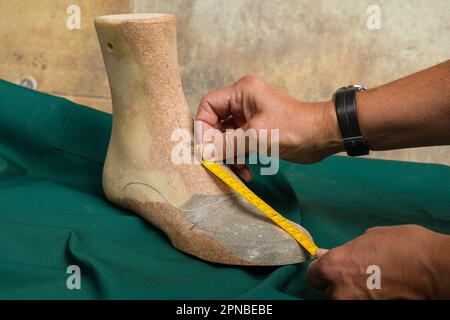 mani di un calzolaio ortopedico che misura una forma di legno lavorata individualmente Foto Stock