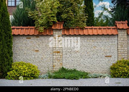 Moderna struttura in mattoni con pareti di recinzione in pietra chiara con piastrelle di fronte ad un edificio residenziale. Foto Stock