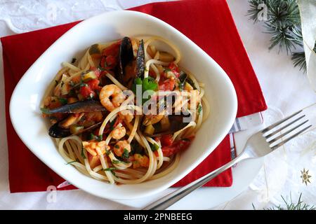 Spaghetti con frutti di mare. Tavolo natalizio festivo per la cena festiva con piatti. Concetto di ricongiungimento familiare. Stagione di festa. Vista dall'alto. Foto Stock