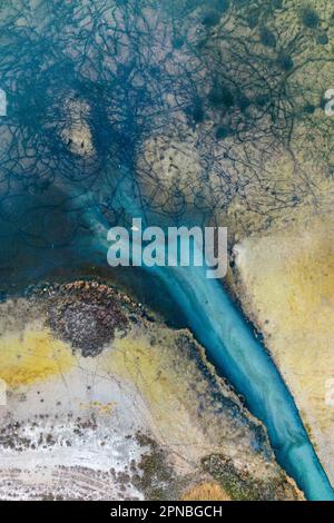 Spettacolare vista aerea dello stretto fiume con acqua turchese che scorre tra alti alberi autunnali che crescono nella foresta alla luce del sole Foto Stock
