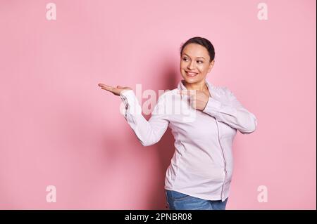 Bella donna buisnesswoman grigio femmina, manager sorride e punta il suo indice dito a copia spazio annuncio sulla sua mano palmo in su Foto Stock