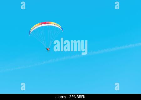 Parapendio irriconoscibile che vola attraverso il cielo con istruttore di parapendio, spazio copia incluso Foto Stock