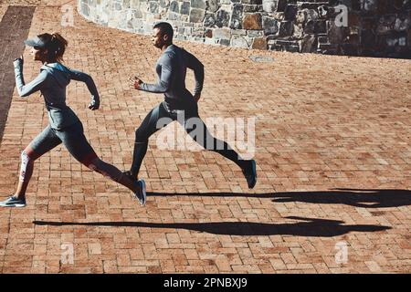 Impegnarsi l'un l'altro in strada. Foto a tutta lunghezza di due giovani e sportivi che corrono per la città. Foto Stock