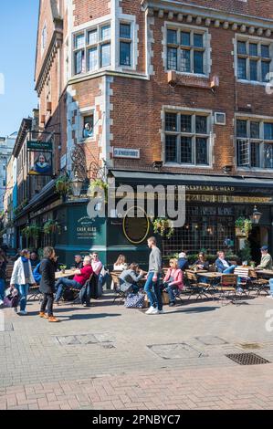 Persone che si rilassano e gustano un drink seduti fuori dal pub Shakespeares Head in una giornata di sole. Great Marlborough Street, Carnaby, Londra, Inghilterra, Regno Unito Foto Stock