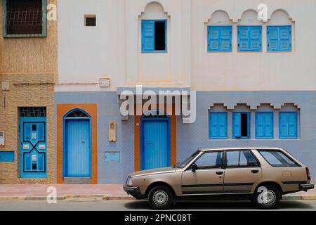 Sidi Ifni, Marocco - vintage stazione in bronzo vagone auto parcheggiata all'esterno di un edificio bianco con porte e finestre blu brillante. Stravagante architettura marocchina. Foto Stock