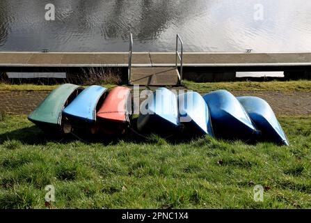 Canoe giacenti su un lato canale erba verga in una mattina di primavera Foto Stock