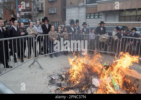 Ore prima dell'inizio della Pasqua ebraica, uomini e ragazzi si preparano bruciando l'ultimo dei loro prodotti di pane. Su Lee Avenue a Brooklyn, New York. Foto Stock